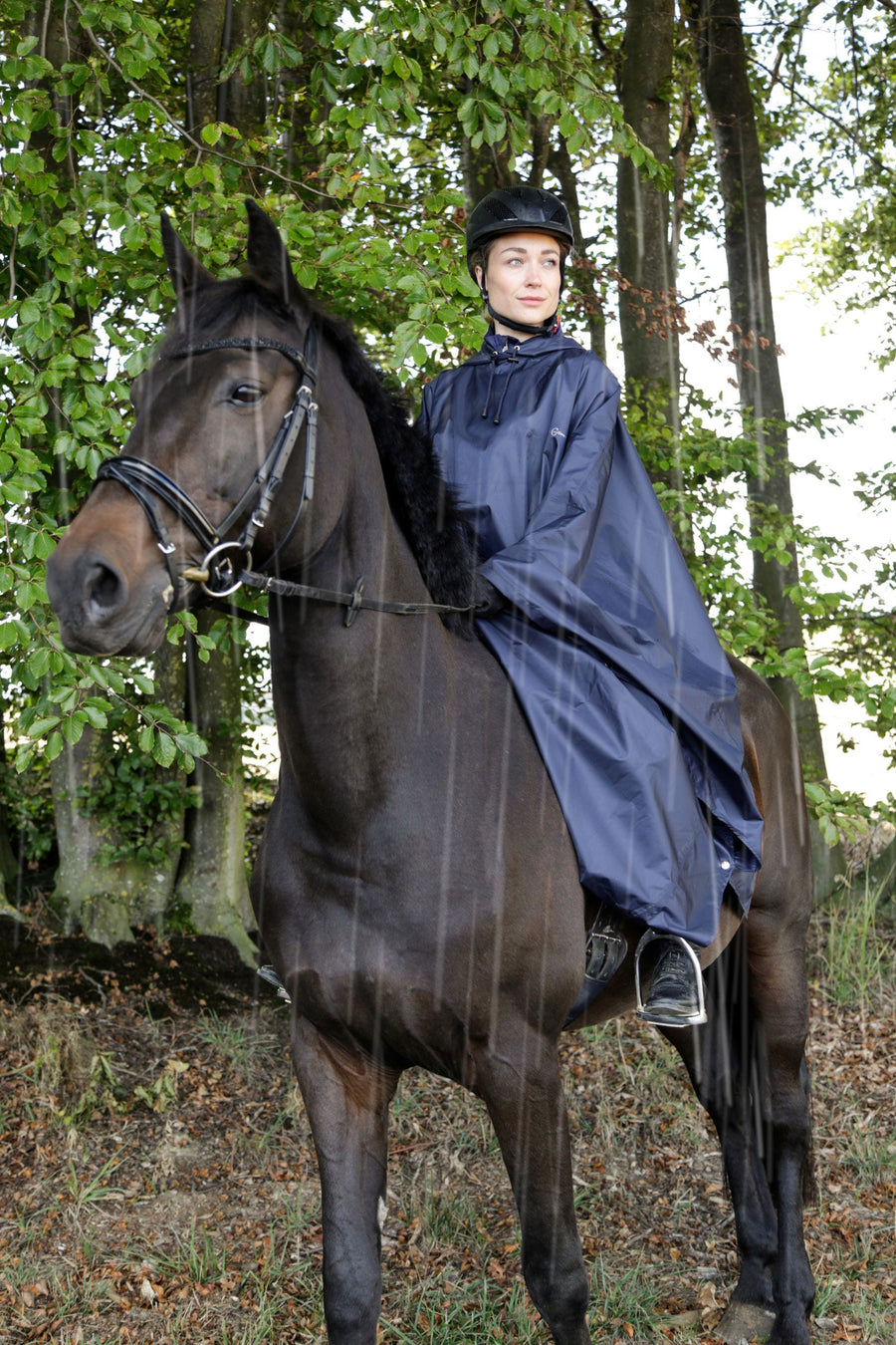 Cavalière à cheval sous un poncho de pluie bleu marine