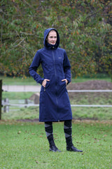 Cavalière en manteau de pluie long bleu marine, debout au pré
