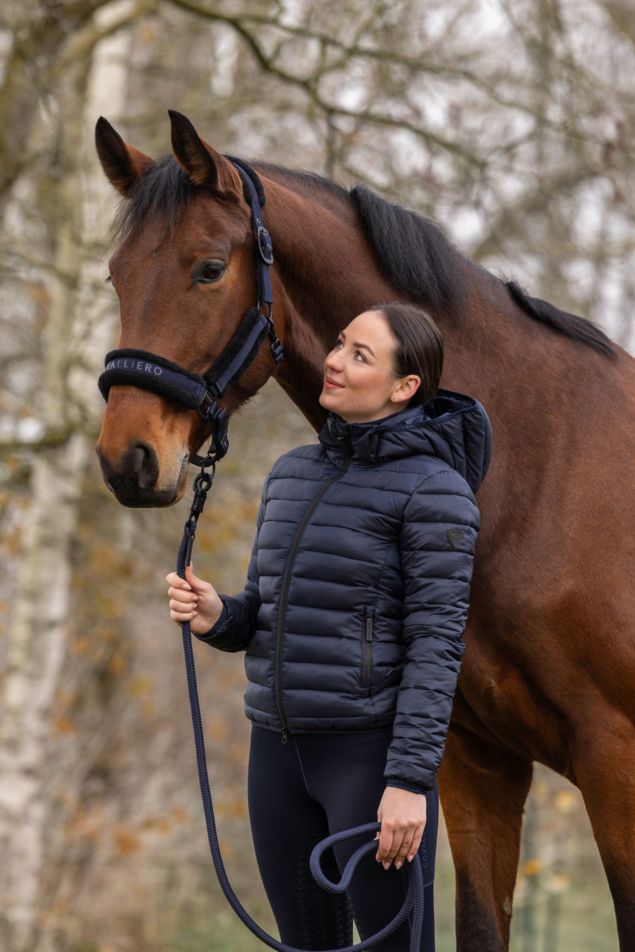 Cavalière en veste matelassée tenant son cheval en longe