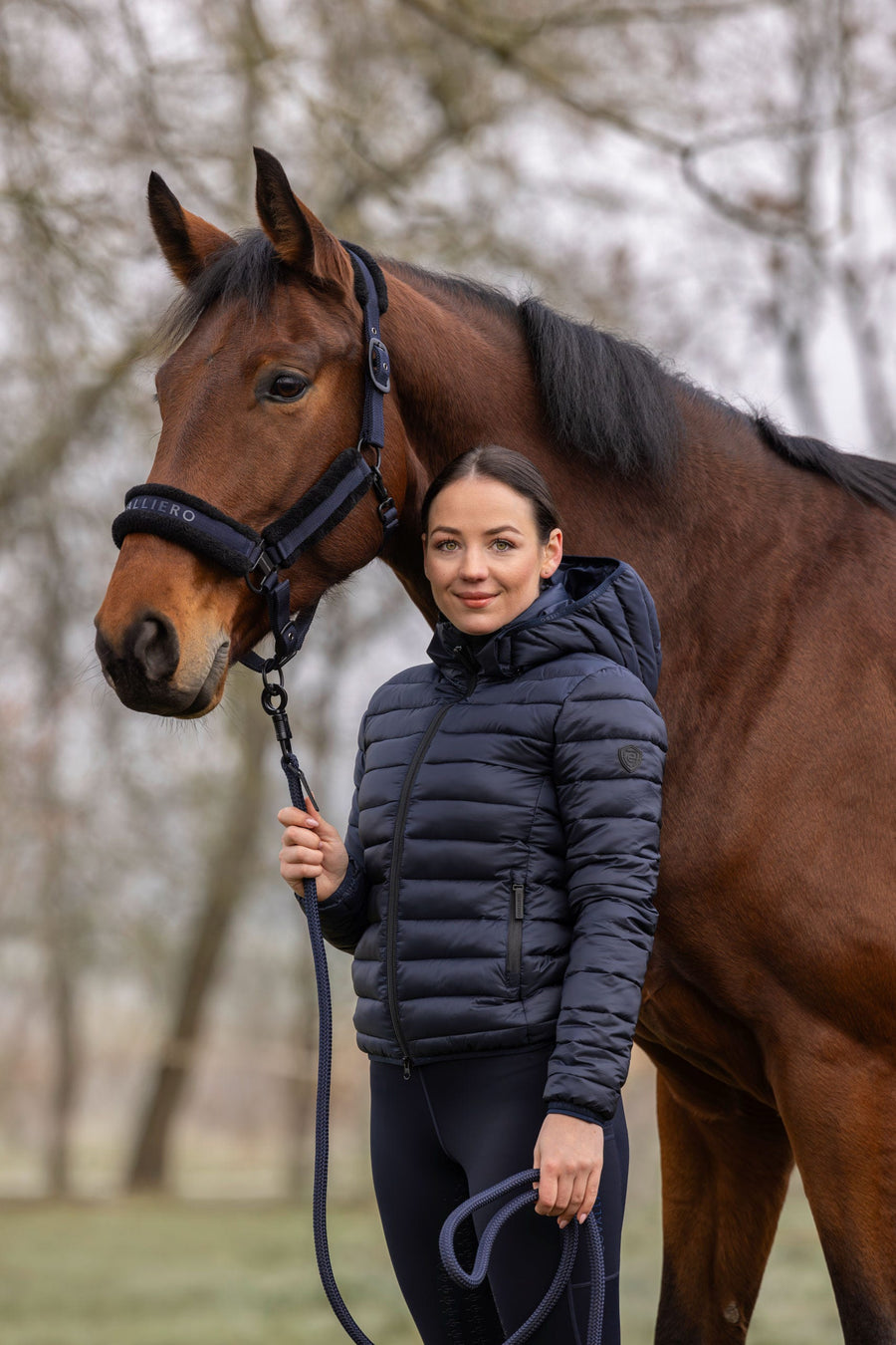 Cavalière en veste matelassée bleu marine, à côté de son cheval