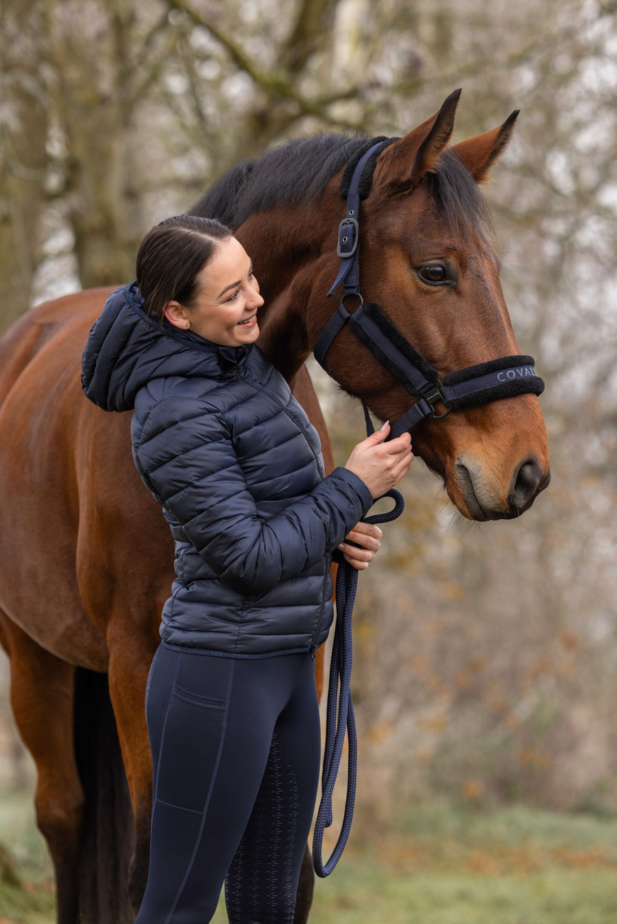 Cavalière en veste matelassée caressant son cheval