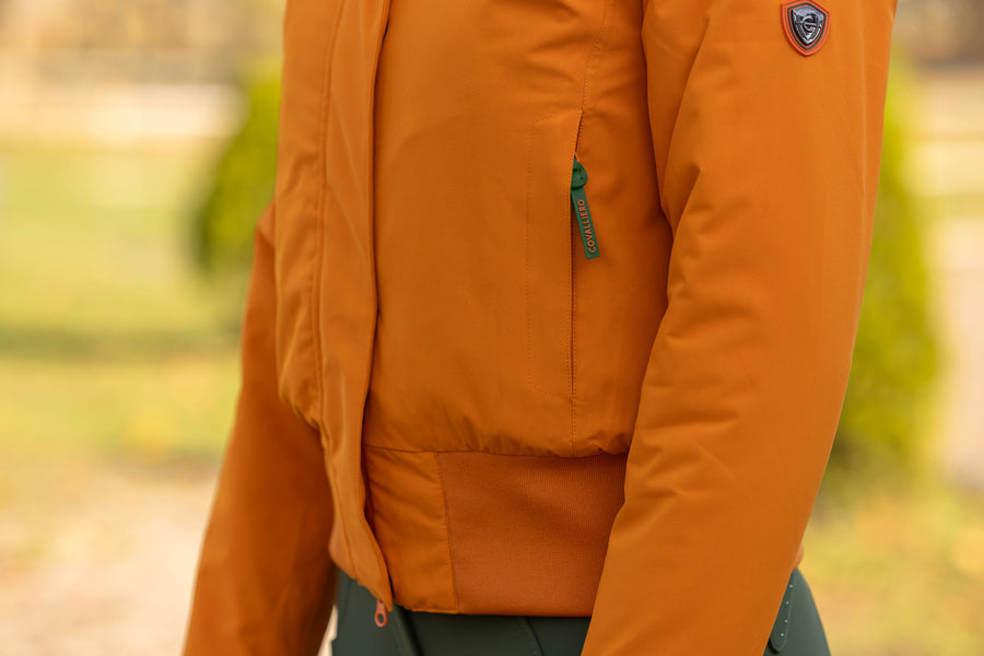 La poche zippée et le bas élastique du blouson orange