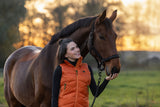 Cavalière en doudoune orange avec son cheval au pré