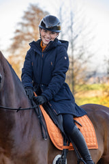 Cavalière souriante à cheval en parka bleu marine