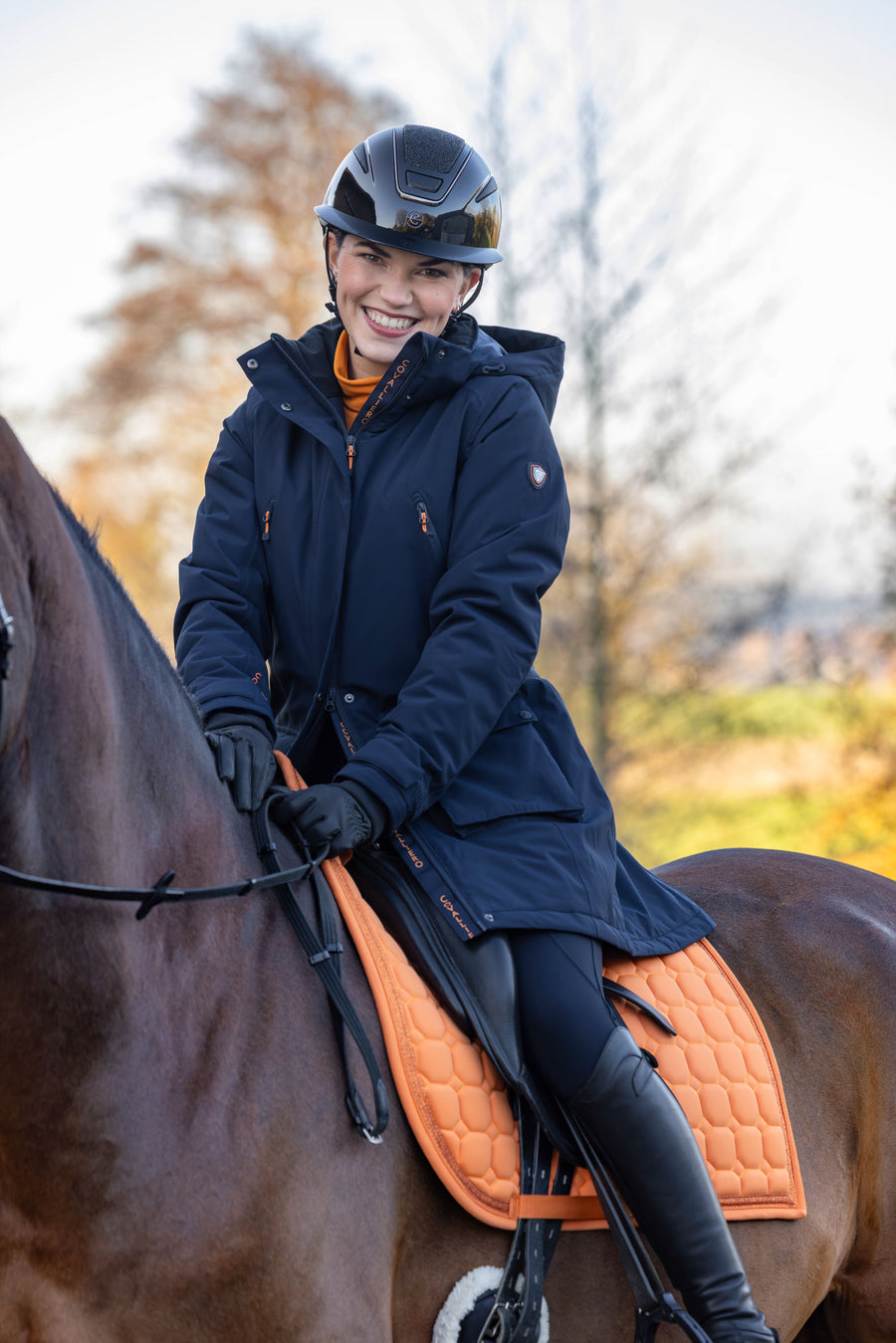 Cavalière souriante à cheval en parka bleu marine