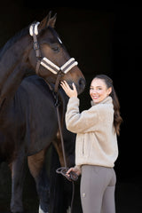 Cavalière en sweat Teddy beige caressant la tête de son cheval