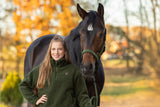 Cavalière en sweat Teddy vert forêt à côté de son cheval, en automne